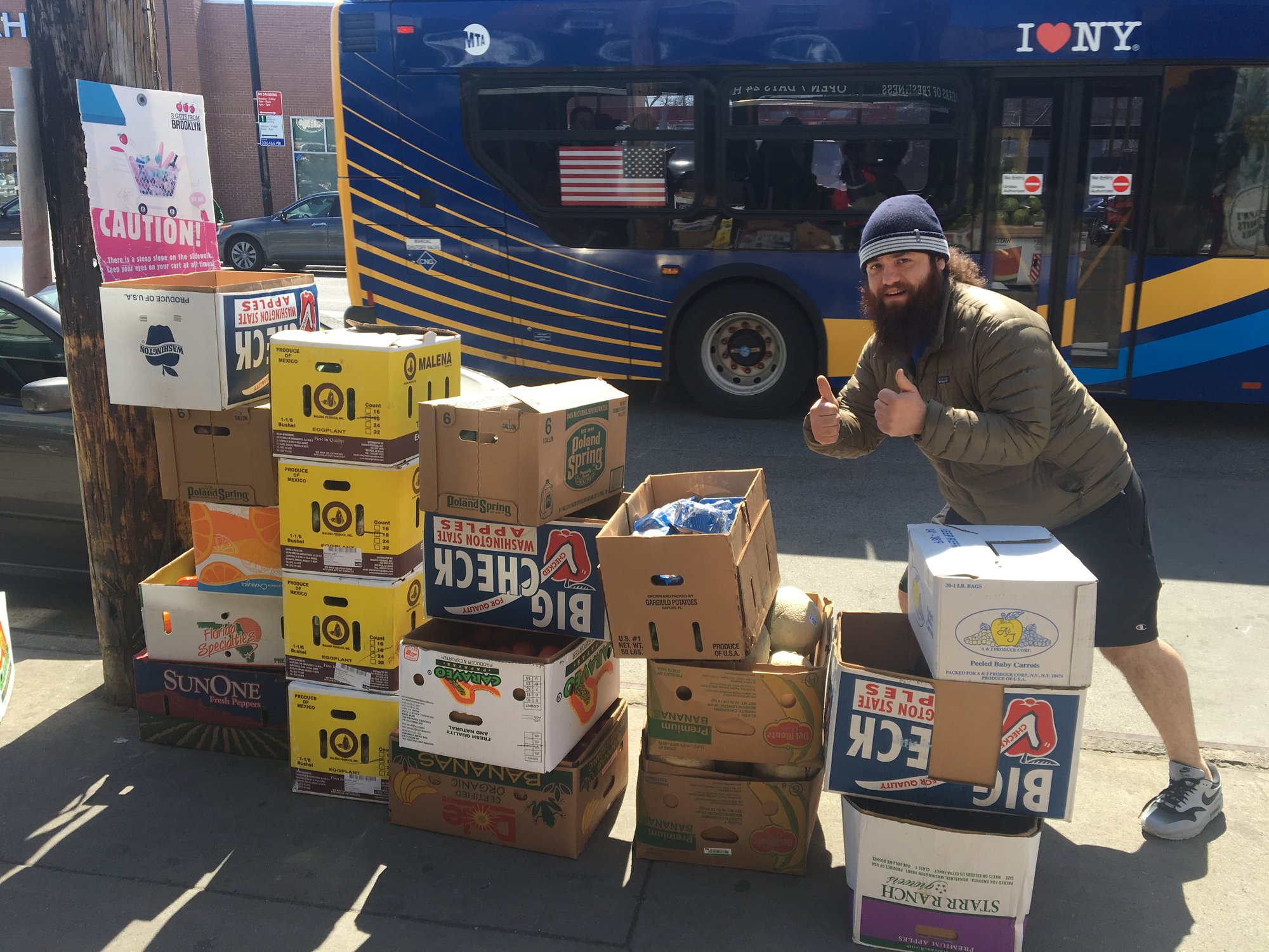 food rescuer posing with many boxes of rescued food on the sidewalk